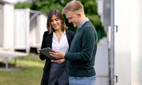 Zwei Experten analysieren die Flexibilitätsvermarktung von Energiepotenzialen an einem Batteriespeicher via Tablet